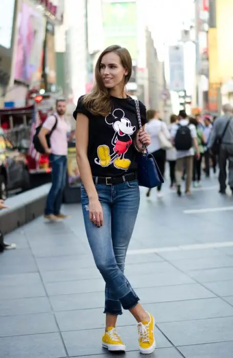 Menina andando na rua e modelando uma roupa com uma camisa estampada do Mickey Mouse