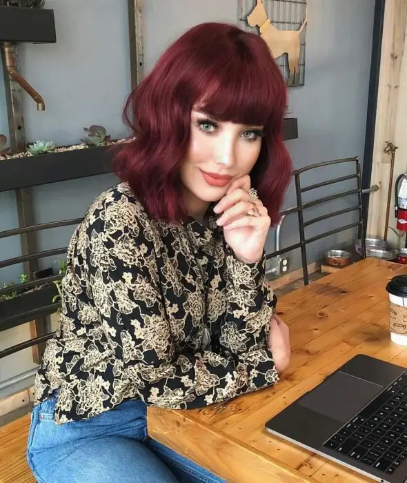 Menina com cabelo ruivo cor de vinho sentada em um restaurante