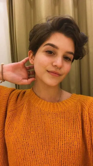 Menina com corte pixie e suéter laranja