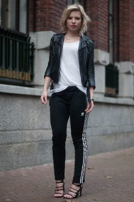 Menina vestindo calça preta com jaqueta de couro e sandálias pretas 