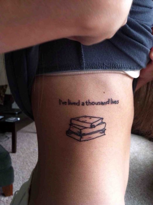 menina com uma tatuagem com frases e livros colocados na lateral do corpo 