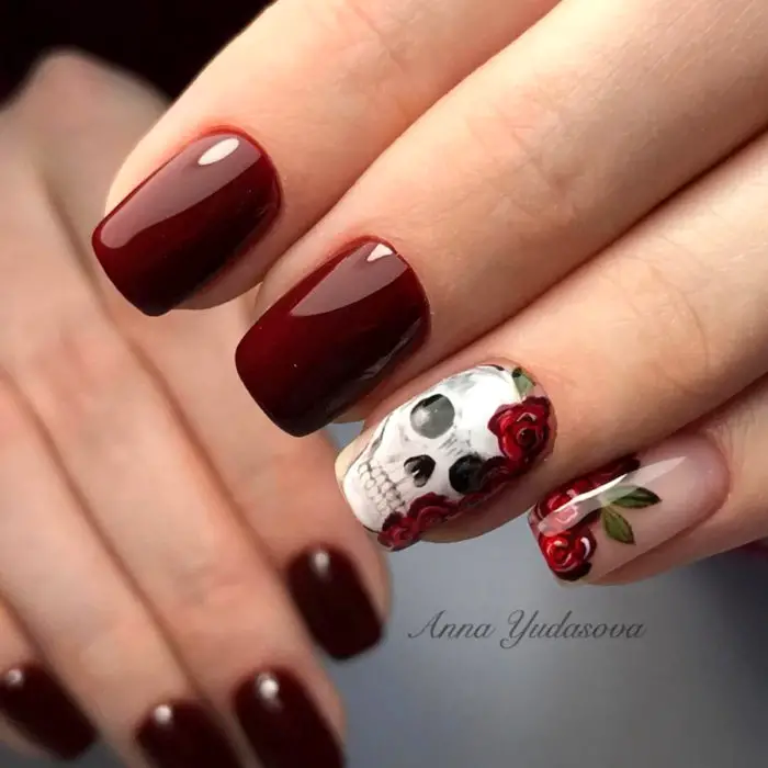 Manicure do Dia dos Mortos;  unhas quadradas compridas pintadas com esmalte vermelho vinho e caveira de flores