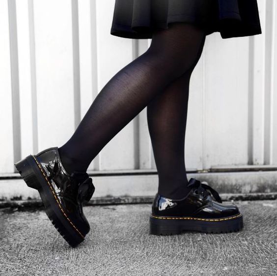 Pernas femininas com meias pretas e sapatos plataforma largos