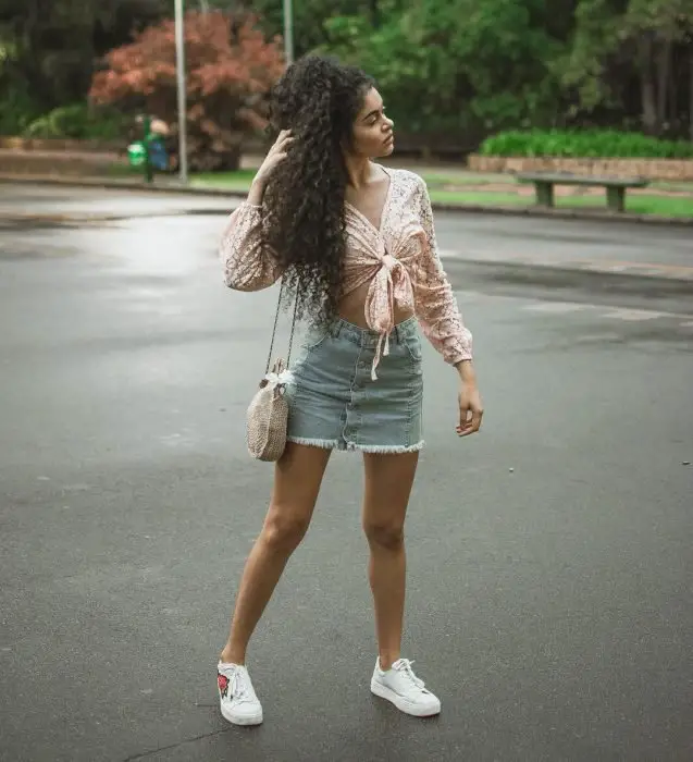 Menina chinesa de cabelo no meio da rua de saia jeans e tênis