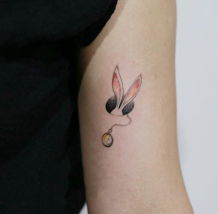 Tatuagem minimalista das orelhas e do relógio do coelho de Alice no País das Maravilhas no braço