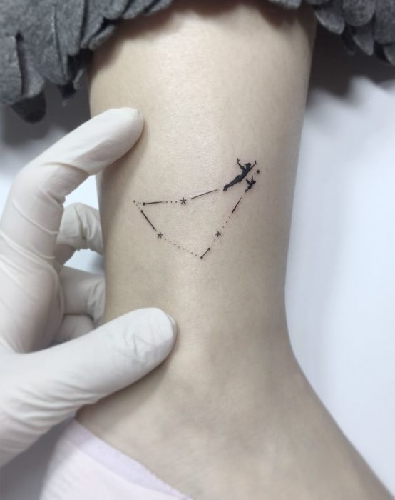 Tatuagem minimalista de Peter Pan voando em uma constelação no tornozelo