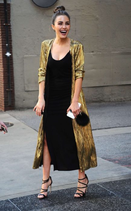 Menina usando um vestido preto com um conjunto dourado e bolsa clutch de veludo 