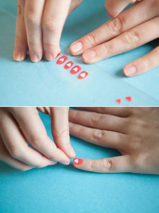 mulher tirando selos de um papel para colocá-los nas unhas 