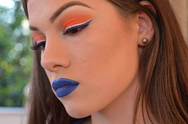 mulher com maquiagem laranja e lábios azuis 