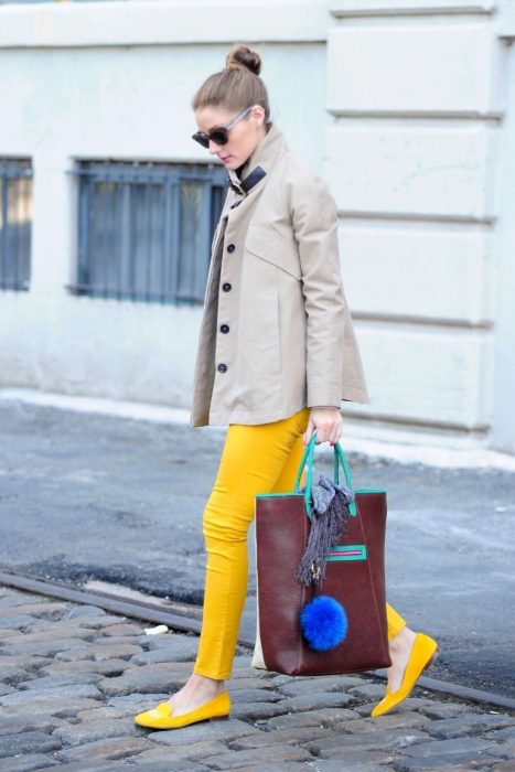 Menina vestindo calça e sapatos amarelos, um sobretudo e uma bolsa marrom