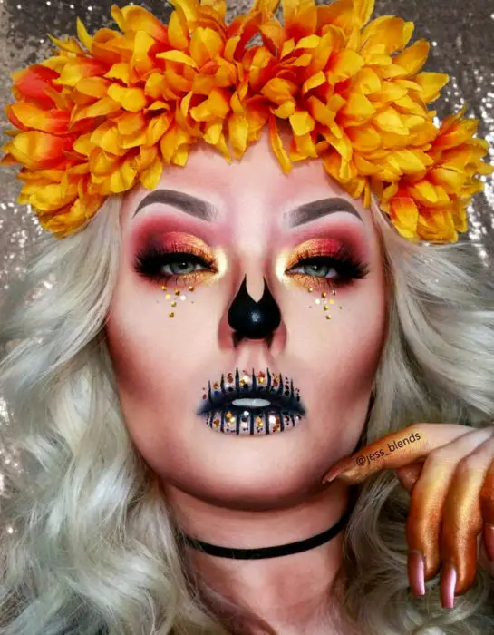 Modern Day of the Dead Maquiagem Catrina com flores de calêndula no cabelo, olhos com sombras laranja e lantejoulas