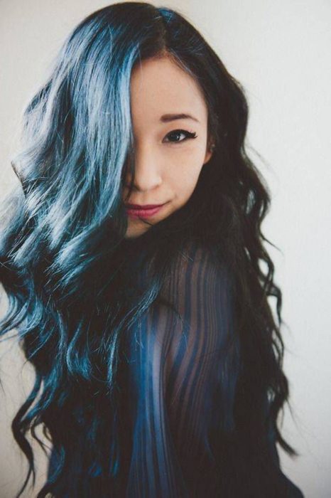 Menina cobrindo o rosto com cabelos longos com mechas em azul 