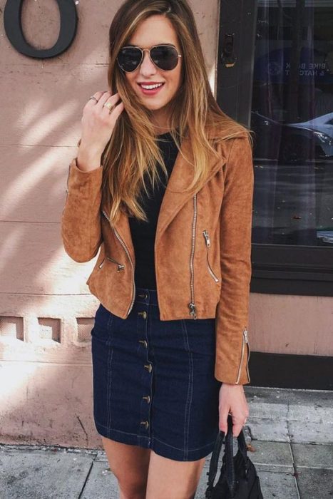 garota vestindo jaqueta de couro marrom e saia jeans 