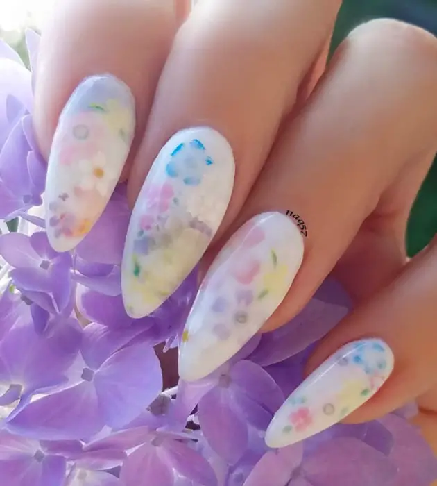 Desenhos de manicure para banhos de leite;  unhas longas brancas de estilete com flores roxas, azuis, amarelas e rosa