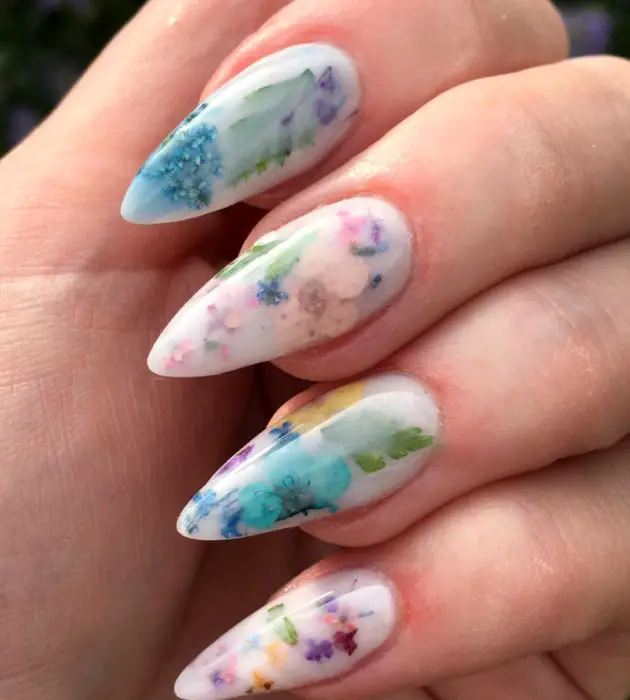 Desenhos de manicure para banhos de leite;  unhas longas e brancas com flores azuis, rosa, amarelas e roxas
