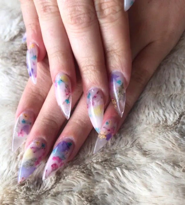 Desenhos de manicure para banhos de leite;  unhas longas de estilete lilás com flores rosa, amarelas e azuis