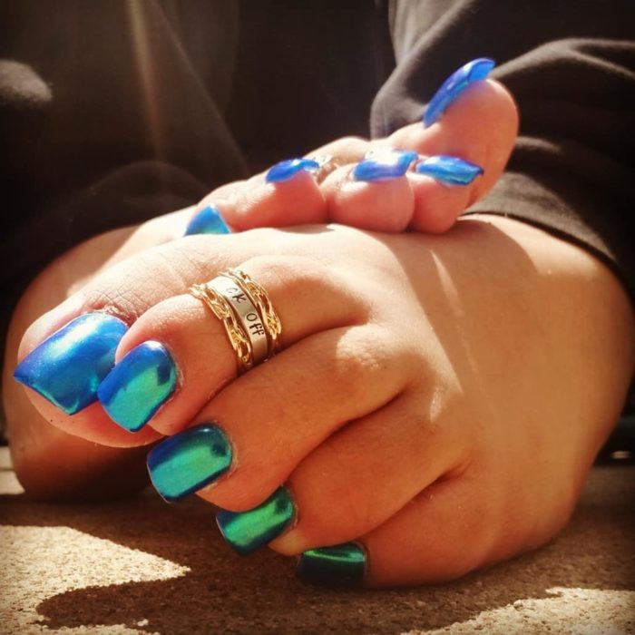 Menina com unhas de acrílico azul iridescente nos pés 