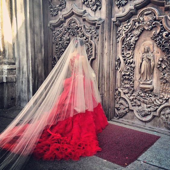 Uma noiva em um vestido vermelho e véu branco nos portões de um templo