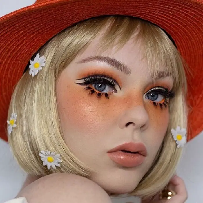 menina loira com chapéu laranja com maquiagem em cores laranja
