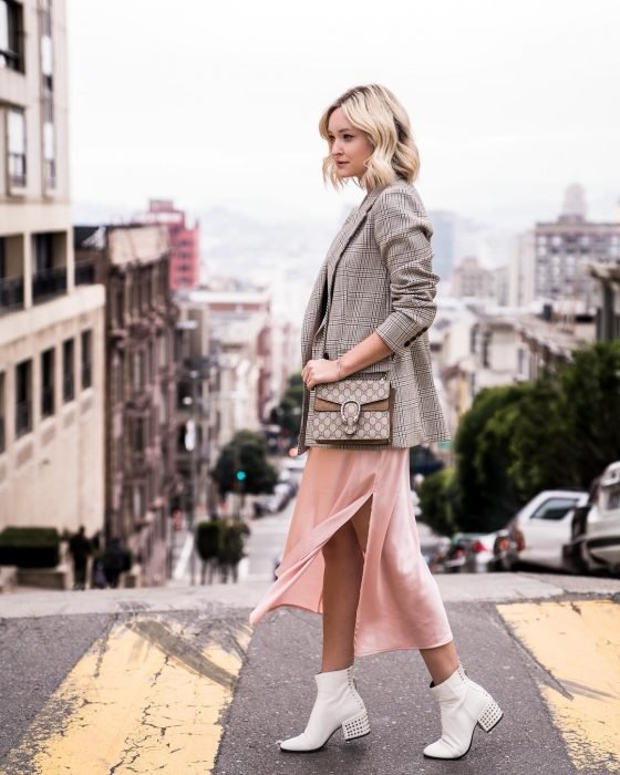 menina com saia rosa, botas, bancos e jaqueta cinza