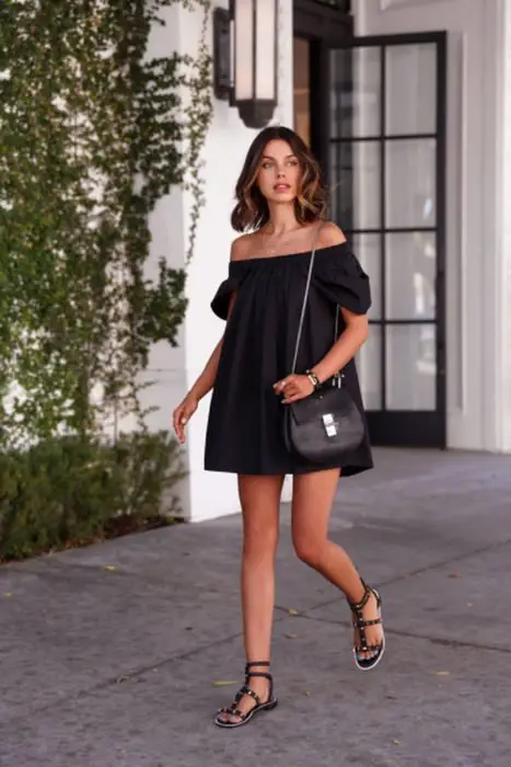 Menina usando um vestido preto com sandálias pretas 