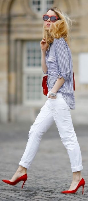 Menina andando pelas ruas vestindo calça branca, sapato vermelho e blusa azul 
