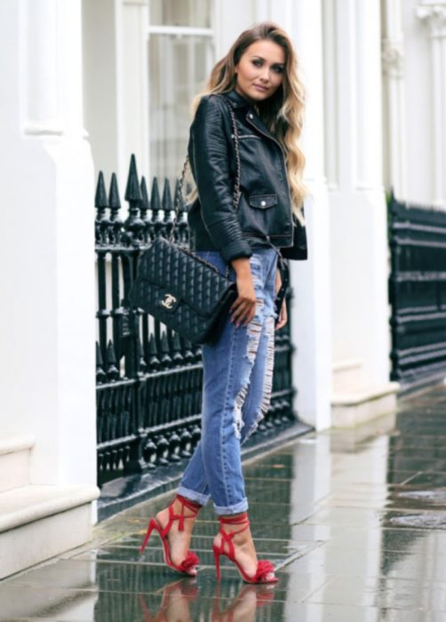 Garota parada na rua usando jeans, jaqueta de couro e sapatos vermelhos 