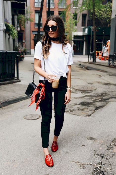 Menina andando na rua vestindo uma roupa preta e branca com sapatos vermelhos 