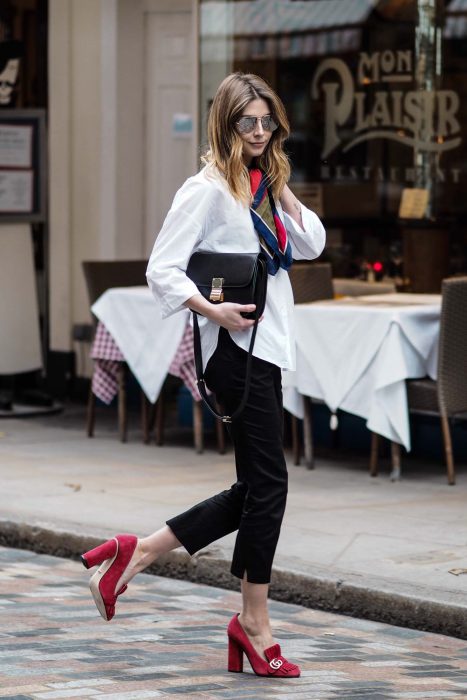 Menina andando na rua vestindo uma roupa preta e branca e sapatos quadrados vermelhos 