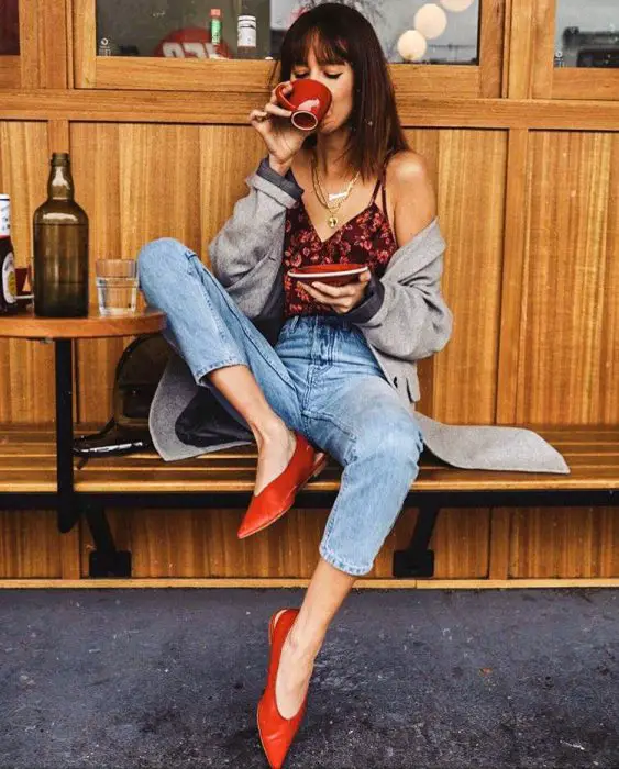 Menina sentada tomando café enquanto mostra seus sapatos vermelhos