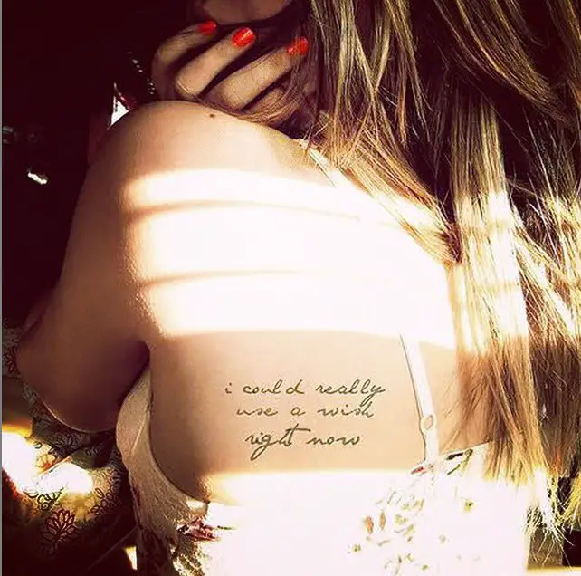 tatuagem de frase nas costas de uma garota que toma sol 