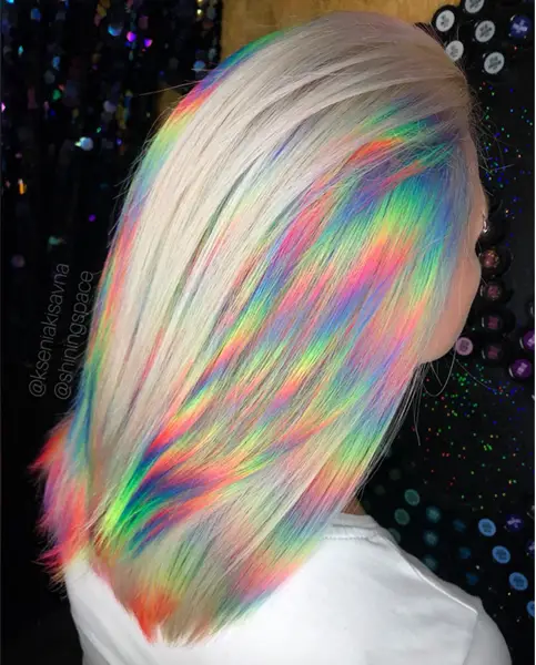 Garota por trás mostrando seu cabelo loiro com reflexos holográficos coloridos 